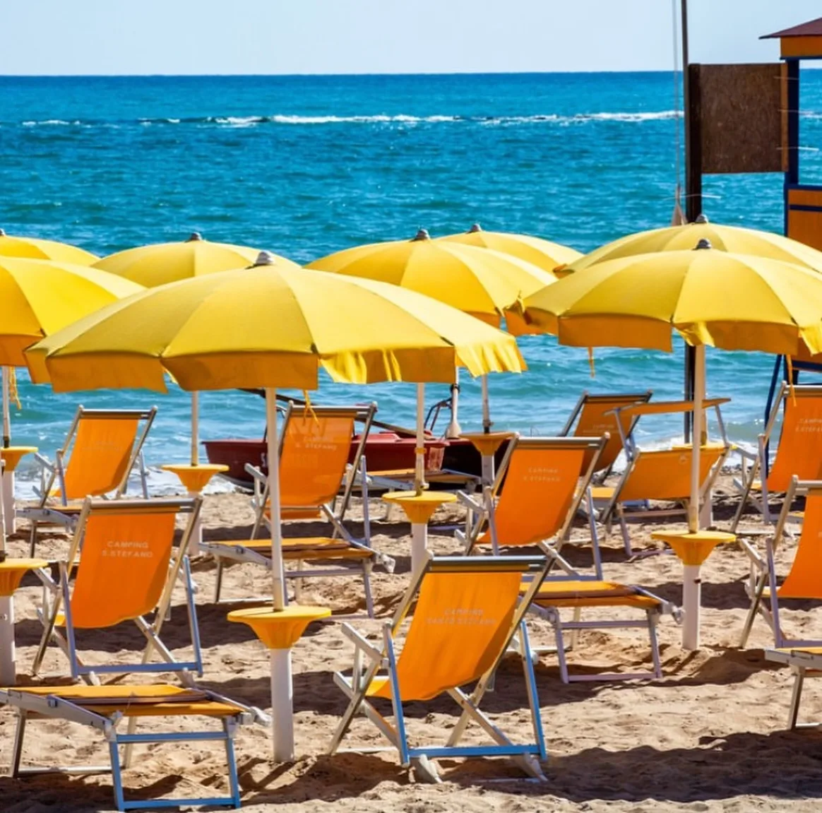 Ombrelloni gialli e sedie a sdraio arancioni in uno stabilimento balneare in riva al mare