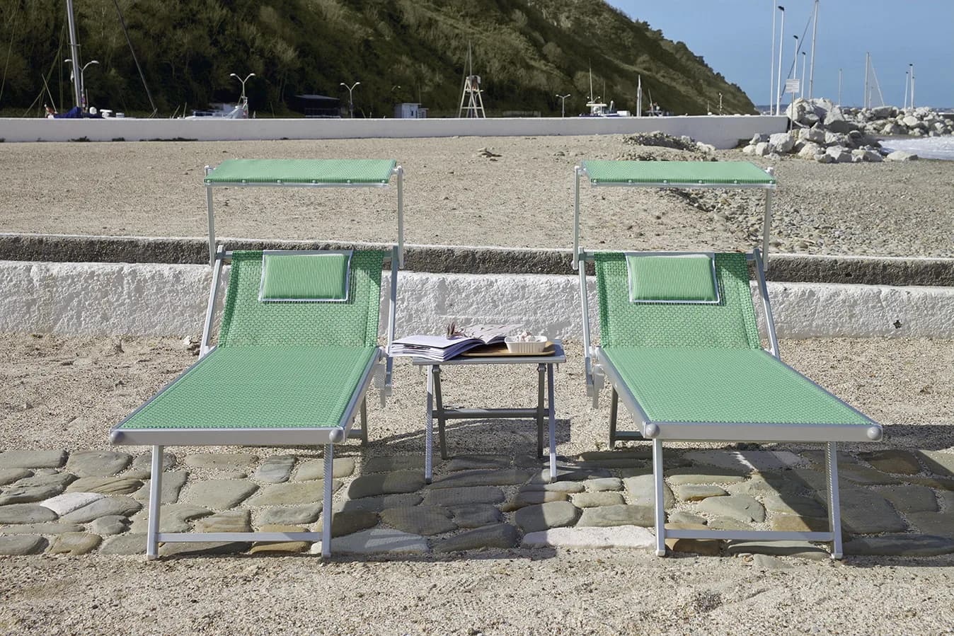 Coppia di lettini verdi con tettuccio parasole e tavolino in uno stabilimento